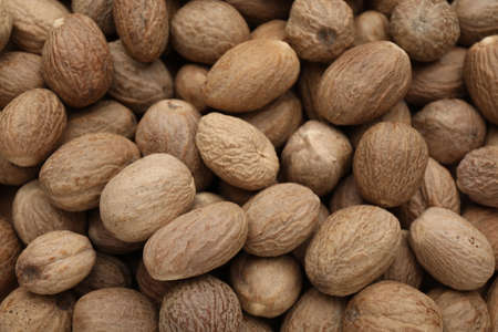 Heap of nutmeg seeds as background, closeupの写真素材