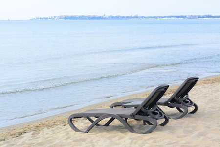 Empty black sunbeds near water on sea beach