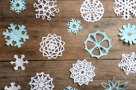 Many paper snowflakes on wooden background, flat lay