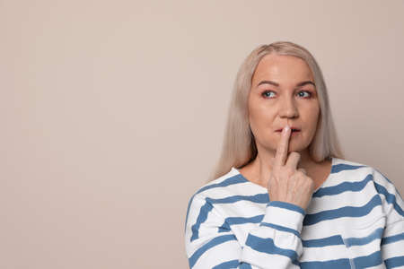 Thoughtful mature woman on beige background. Space for text
