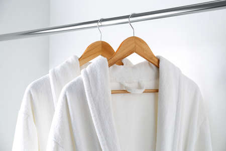 Soft comfortable bathrobes hanging on rack in closetの写真素材