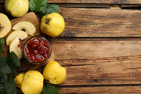 Delicious quince jam and fruits on wooden table, flat lay. Space for textの写真素材