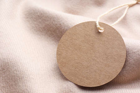 Circle shaped tag with space for text on beige fabric, closeupの写真素材