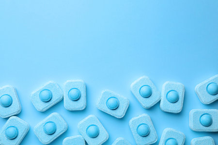 Water softener tablets on light blue background, flat lay. Space for textの写真素材
