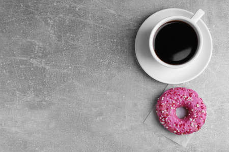 Tasty frosted donut and cup of coffee on light gray table, flat lay. Space for textの写真素材