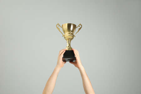 Man holding gold trophy cup on light gray background, closeupの写真素材
