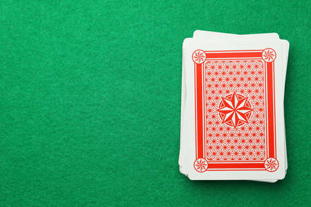 Deck of playing cards on green table, top view. Space for textの写真素材