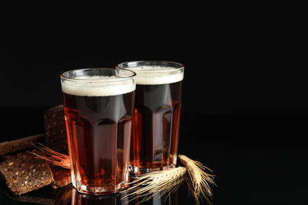 Delicious kvass, bread and spikes on black background. Space for text