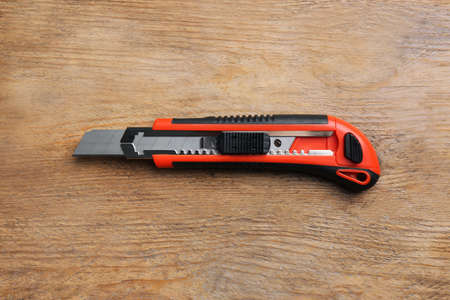 Utility knife on wooden table, top view