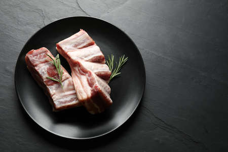 Raw ribs with rosemary on black table, top viewの写真素材