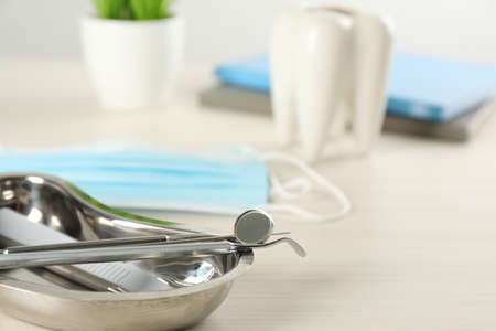 Kidney shaped tray with set of dentist's tools on wooden table, closeup. Space for textの写真素材