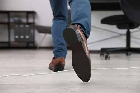 Man tripping over cord in office, closeup