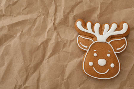 Christmas deer shaped gingerbread cookie on crumpled parchment, top view. Space for textの写真素材