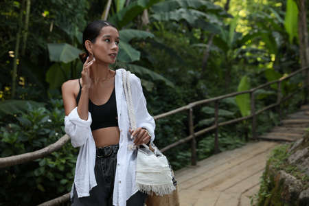 Beautiful young woman in green tropical park, space for text