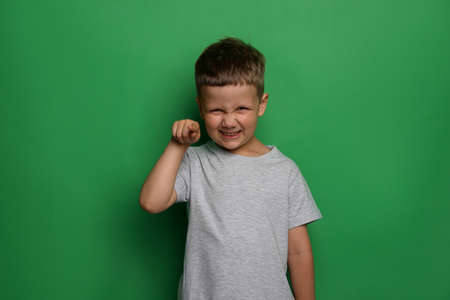 Angry little boy on green background. aggressive behavior