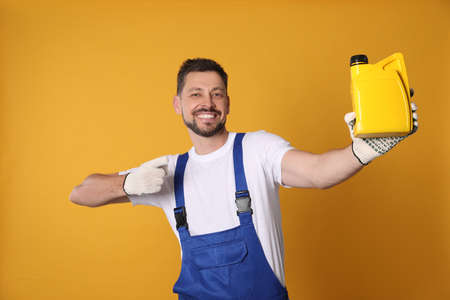 Man pointing at yellow container of motor oil on orange background