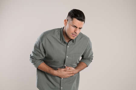Man suffering from stomach ache on beige background. food poisoningの写真素材