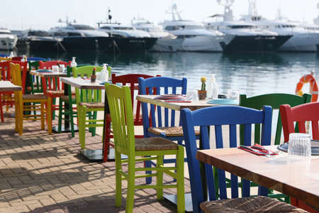 Beautiful view of outdoor cafe with colorful wooden chairs near pierの写真素材