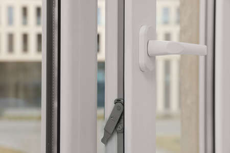 Open window with white plastic frame indoors, closeup