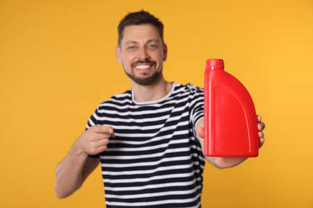 Man pointing at motor oil against orange background, focus on hand containerの写真素材