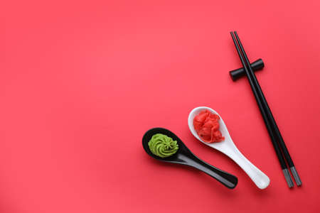 Swirl of wasabi paste, pickled ginger and chopsticks on red background, flat lay. Space for textの写真素材