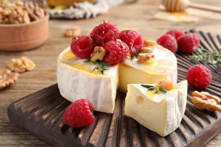 Brie cheese served with raspberries, walnuts and honey on wooden table, closeupの写真素材