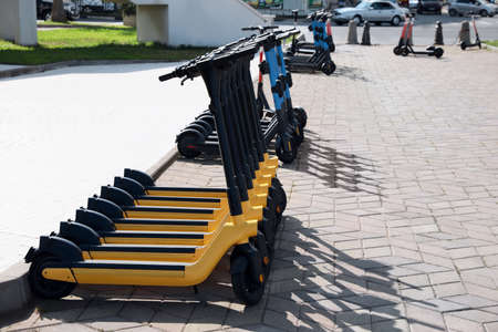 Many modern electric scooters on city street, space for text. rental service