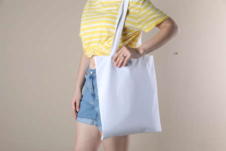 Woman with textile bag on beige background, closeup. space for design