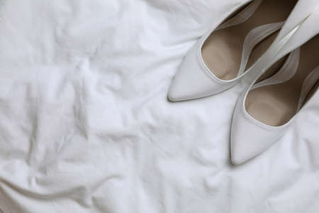 Pair of wedding high heel shoes on white fabric, flat lay. Space for textの写真素材