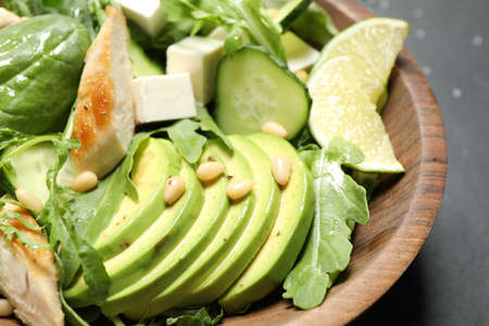 Delicious salad with chicken, arugula and avocado in bowl on table, closeup
