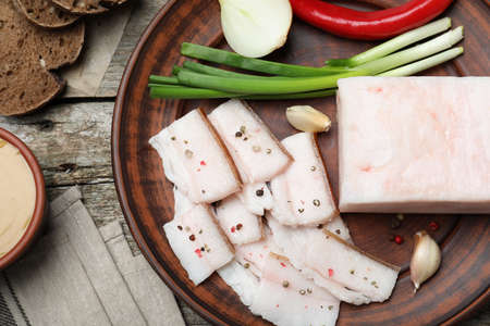 Tasty salt pork with vegetables served on wooden table, flat lay