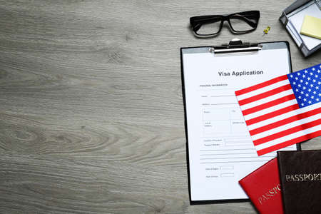 Visa application form, American flag, passports and stationery on wooden table, flat lay. Space for textの写真素材
