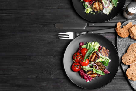 Delicious salad with roasted eggplant and basil served on black wooden table, flat lay. Space for textの写真素材