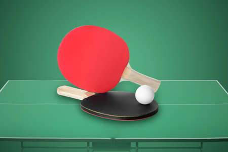 Paddles and ball on  table tennis table against green backgroundの写真素材