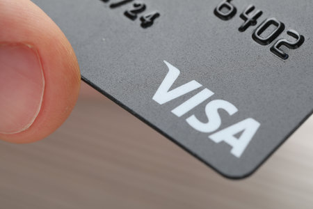 MYKOLAIV, UKRAINE - FEBRUARY 22, 2022: Woman holding Visa credit card on gray background, closeupのeditorial素材