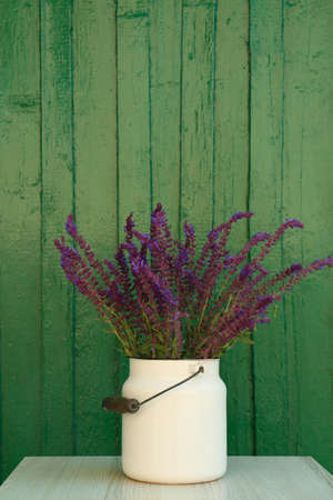 Beautiful bouquet with field flowers in can on white wooden table