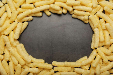 Frame of corn sticks on dark gray table, top view. Space for text