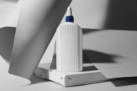 Bottle of glue and paper on gray background