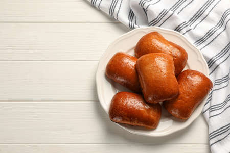 Delicious baked pirozhki on white wooden table, top view. Space for textの写真素材