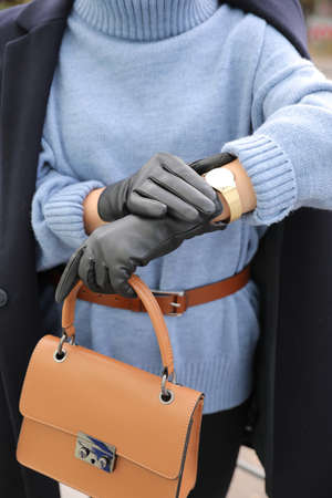 Young woman with stylish black leather gloves and bag outdoors, closeup