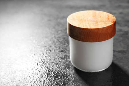 Jar of cosmetic product on wet gray table, closeup. Space for text