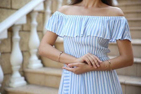 Young woman in stylish light blue striped dress on stairs outdoors, closeupの写真素材