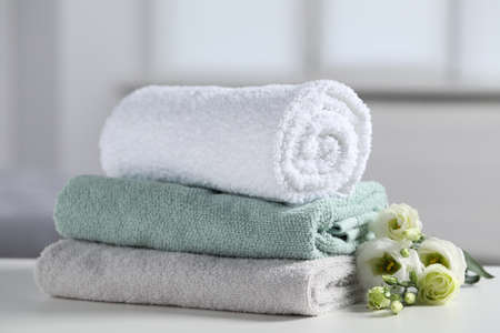 Stack of folded colorful towels with flowers on white table indoors, closeupの写真素材