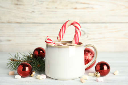 Cup of tasty cocoa with marshmallows, candy cane and Christmas decor on white wooden tableの写真素材