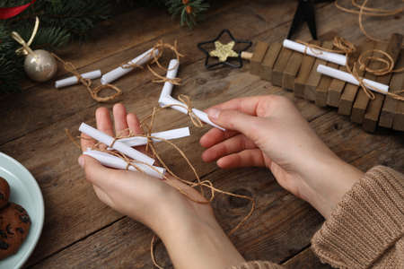 Woman making advent calendar at wooden table, closeup