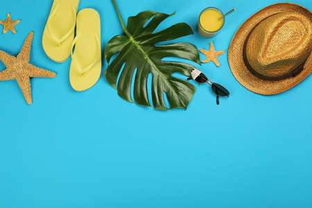 Flat lay composition with beach objects on light blue background, space for text