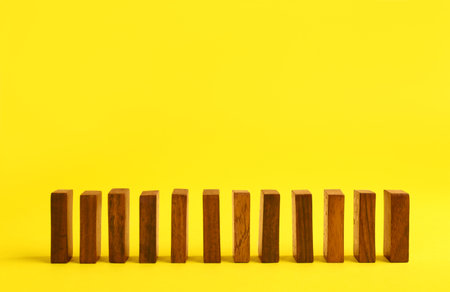 Row of wooden domino tiles on yellow background. Space for textの写真素材