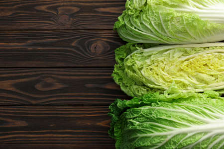Fresh ripe Chinese cabbages on wooden table, flat lay. Space for text