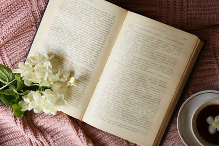 Beautiful jasmine flowers, open book and cup aromatic tea on pink fabric, flat layの写真素材