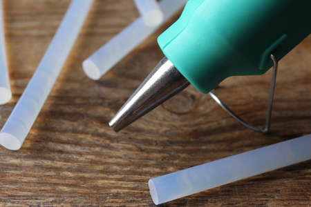 Hot glue gun and sticks on wooden table, closeupの写真素材